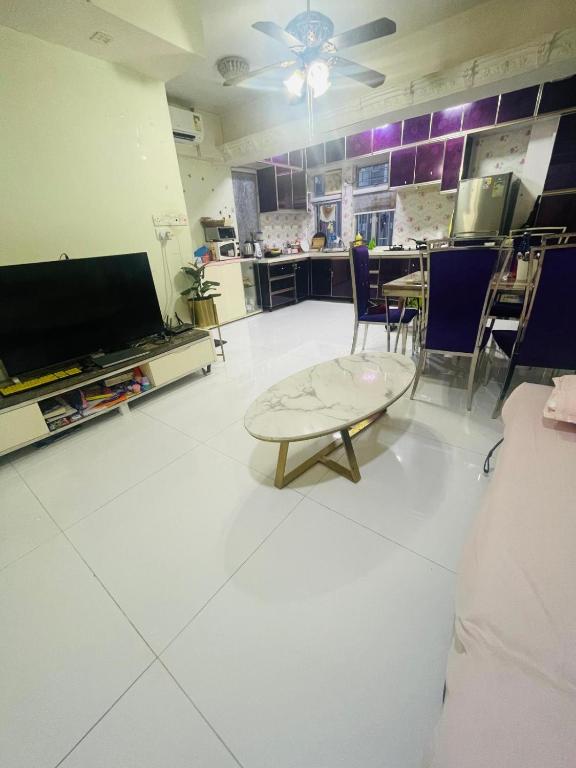 a living room with a tv and a table and chairs at 2 bhk flat available in tst in Hong Kong