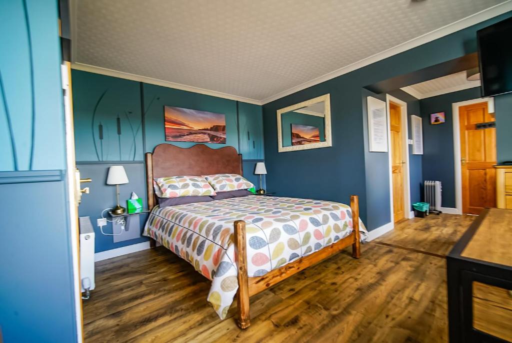 a bedroom with a bed with blue walls and wooden floors at Burnside Cottage in Wick