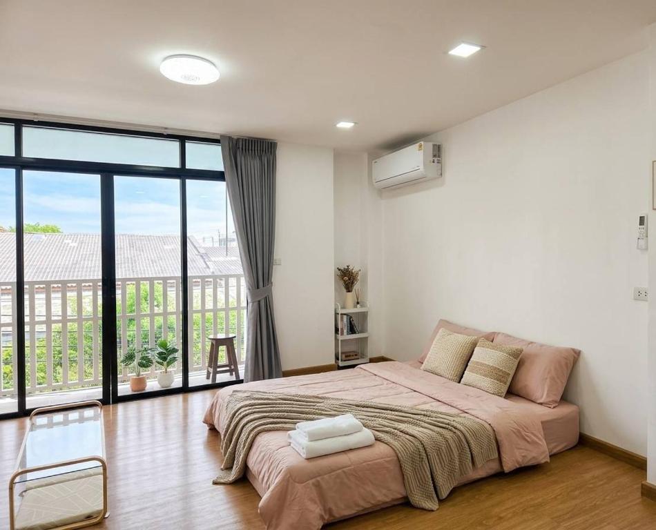 a bedroom with a large bed and a large window at Hugg daily airport in Ban Khlong Thewa