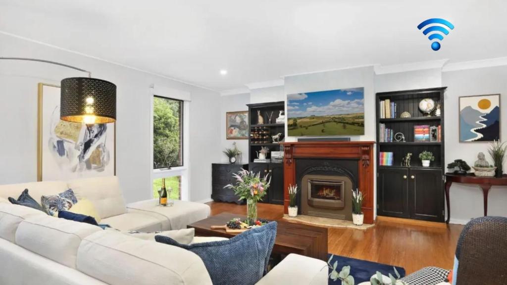 a living room with white furniture and a fireplace at Natures Nest on Nari in Moss Vale