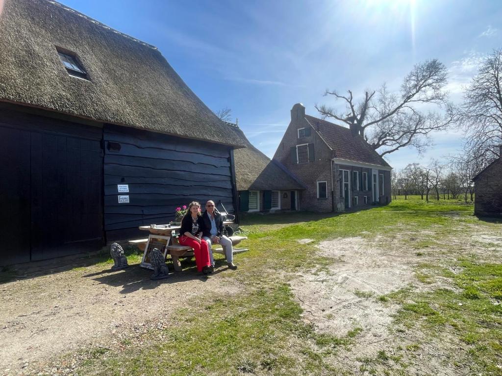 two women sitting on a table in front of a barn at Bed and Breakfast Reestdal in Meppel