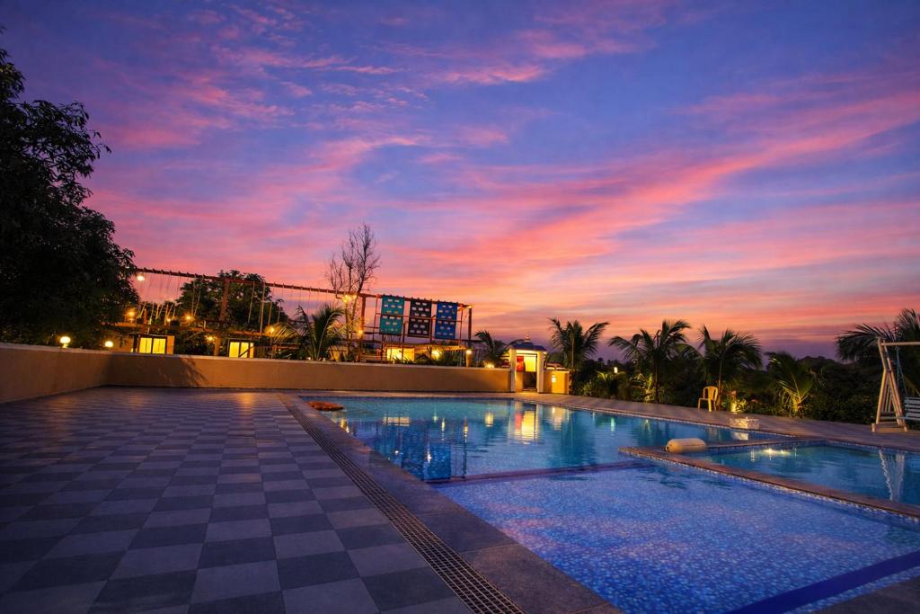 a large swimming pool with a sunset in the background at The Crystal Woods Resort in Mendarda