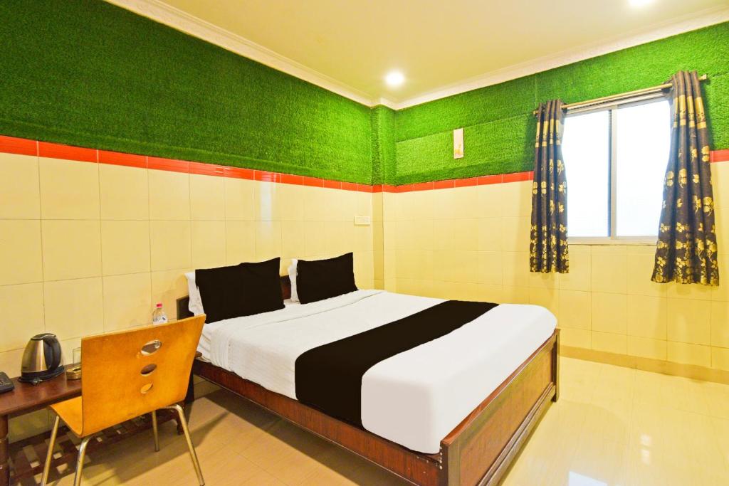 a bedroom with a bed and a desk and green walls at Super Hotel O MAK RESIDENCE in Shamshabad