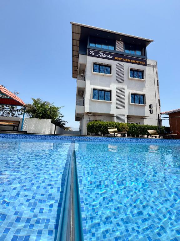 a large swimming pool in front of a building at Hotel Ashoka Kokan Ganpatipule in Ganpatipule
