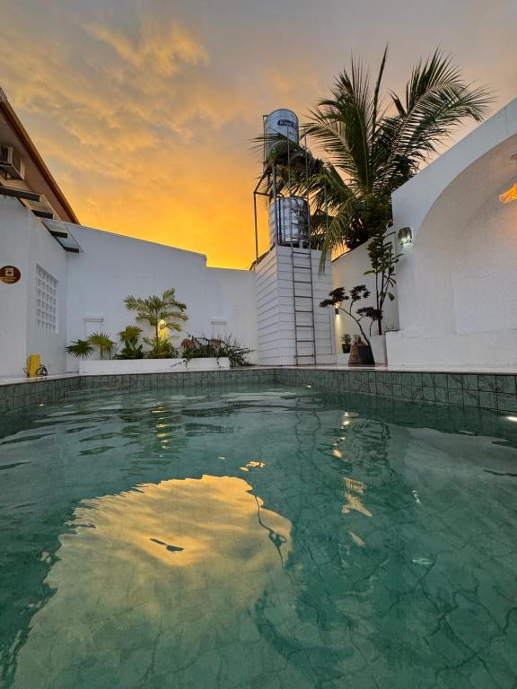 a swimming pool in front of a building with a sunset at Bayu Senja in Lahad Datu