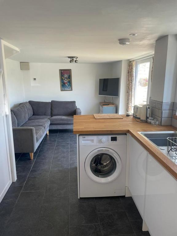 a kitchen and living room with a washing machine at Copswood Cottage in Stroud
