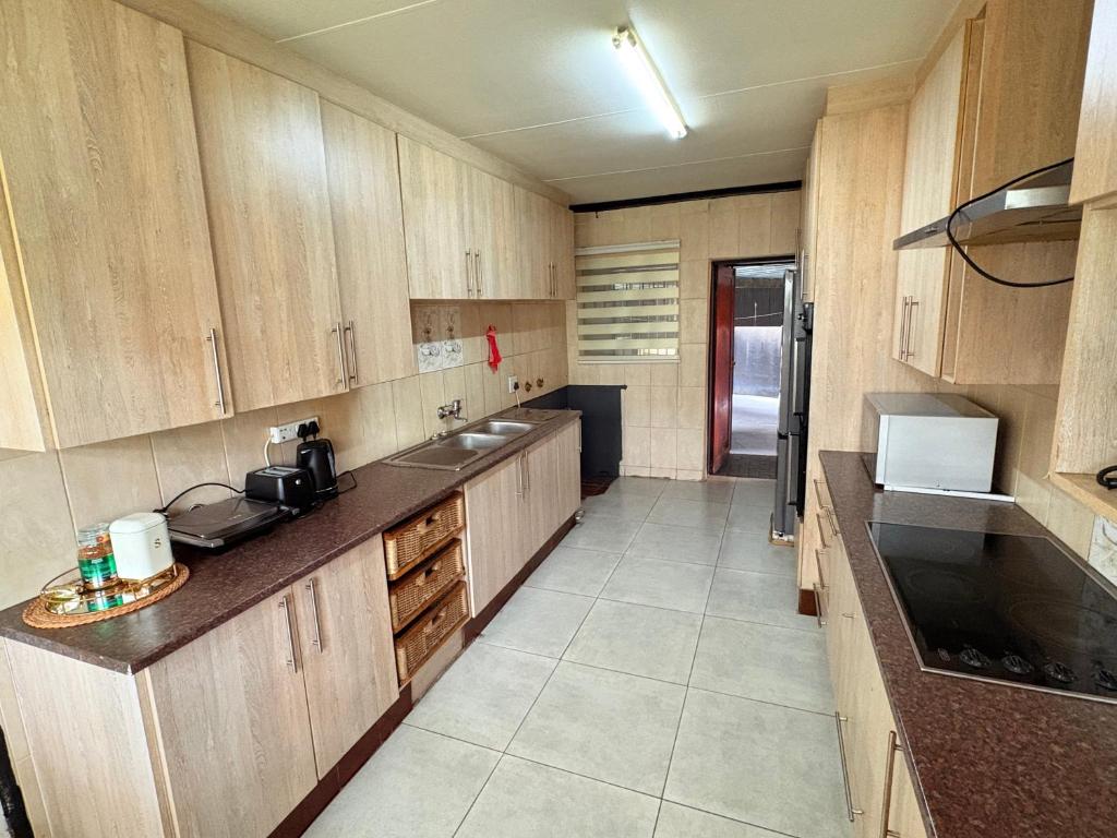 a large kitchen with wooden cabinets and a sink at 38 stay in eMalahleni
