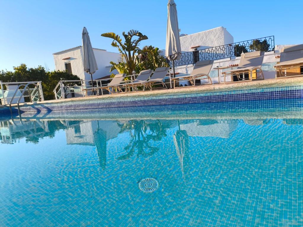 a swimming pool with chairs and an umbrella in the water at Can Joan Yern in Sant Joan de Labritja