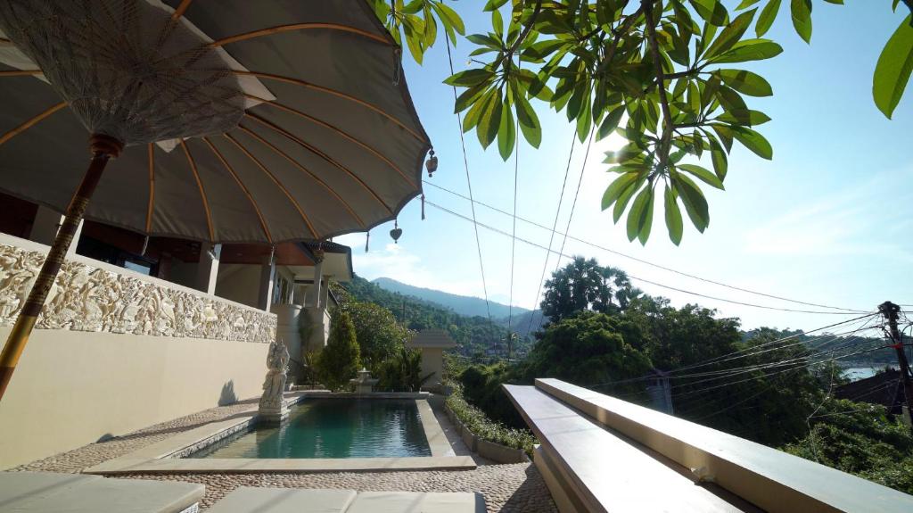 a building with an umbrella and a swimming pool at Bayu - Ocean View - Boutique Hotel in Karangasem