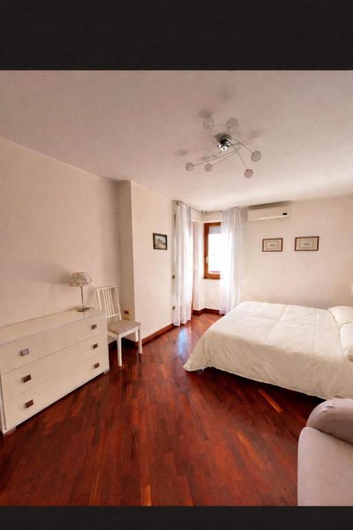 a bedroom with a white bed and a wooden floor at Casa Vista Serapo in Gaeta