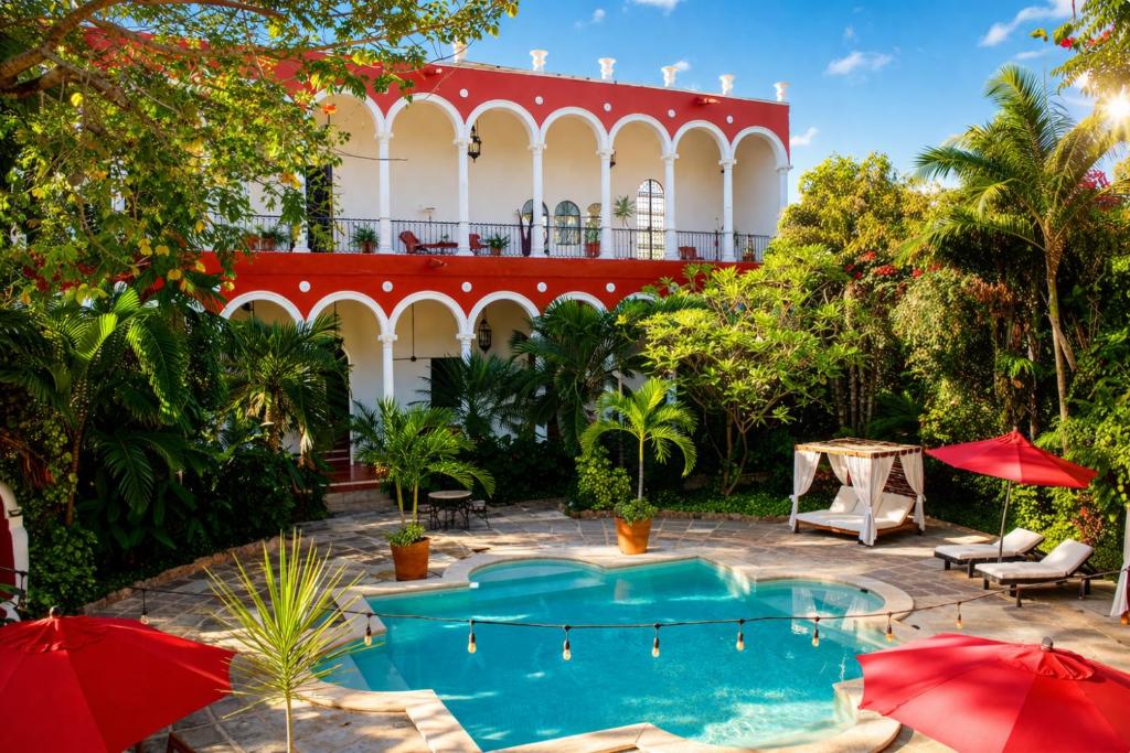 a resort with a swimming pool and red umbrellas at Villa Merida Luxury Mansion - Adults Only Boutique Hotel in Mérida