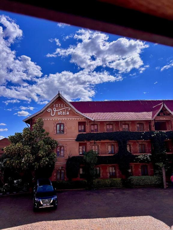 a building with a car parked in front of it at Hotel VATOLA in Antsirabe