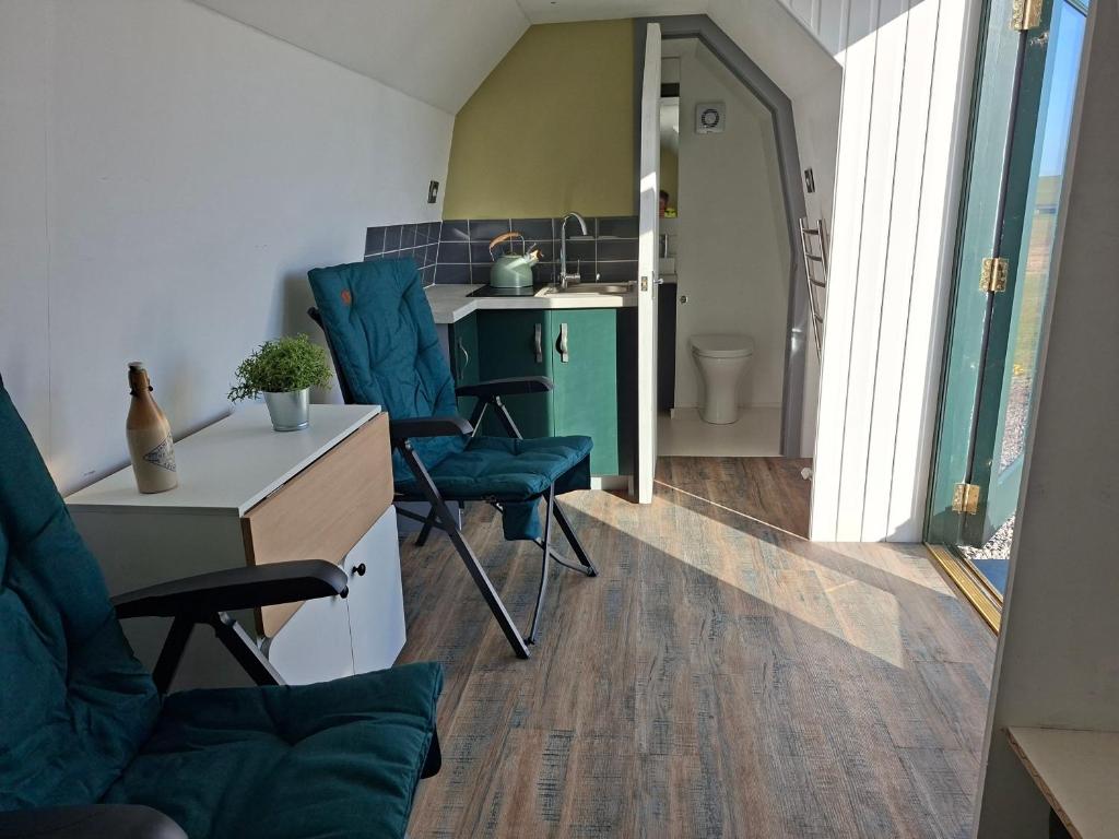 a room with two chairs and a desk and a kitchen at The Orkney Pod in Stromness