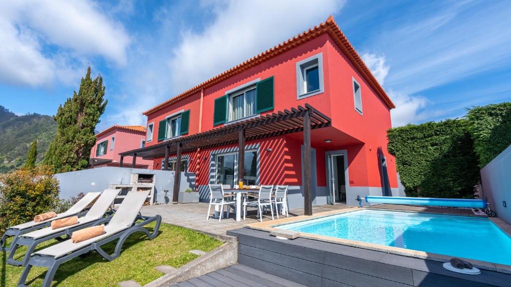 a villa with a swimming pool and a house at DuskLine Villa by LovelyStay in Arco da Calheta