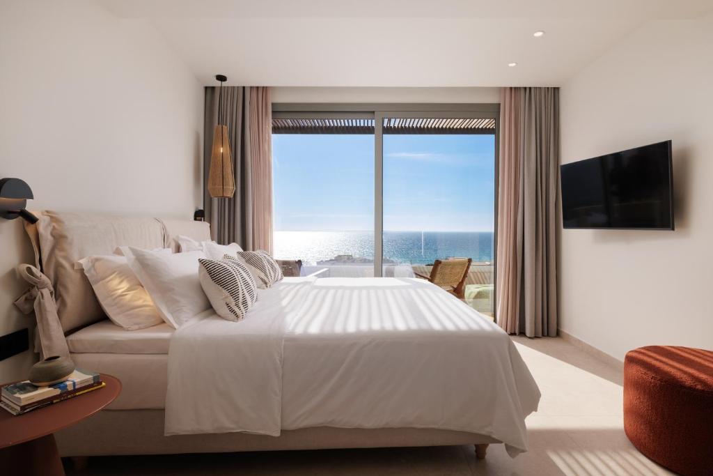 a bedroom with a bed and a view of the ocean at Little Crab Suites in Agios Gordios