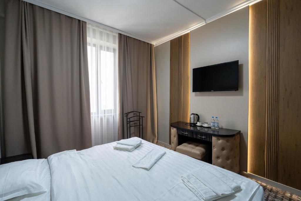 a hotel room with a bed and a desk and a television at DeLuxe PLAZA in Almaty
