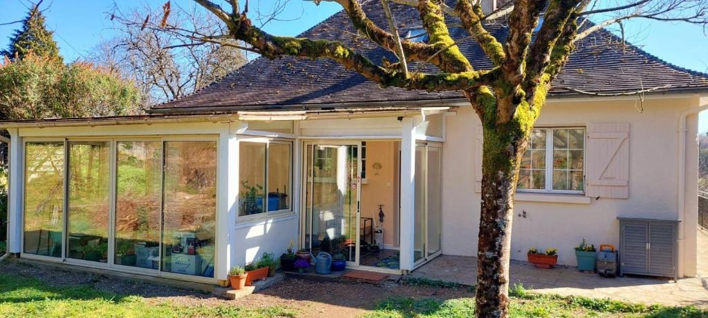 a house with glass doors and a tree at Le Verger Chambres d'hotes in Ségur-le-Château