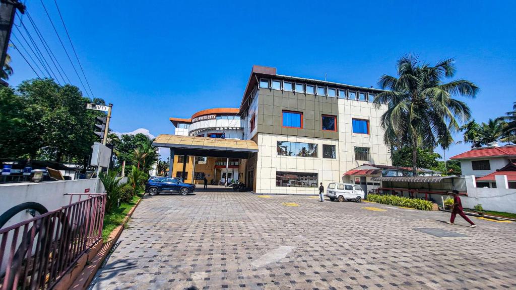 a large building with a cobblestone street in front of it at Hotel White City in North Paravur