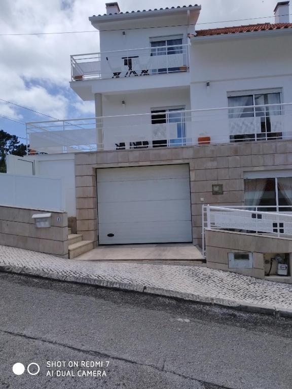 a white house with two garage doors in front of it at Villa Thierry in Leiria