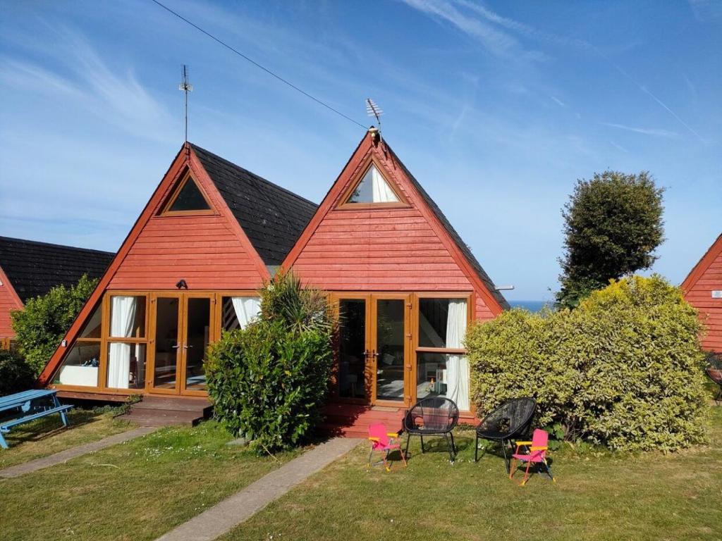 a house with a red roof with chairs in the yard at Chalet Thirtyone in Deal