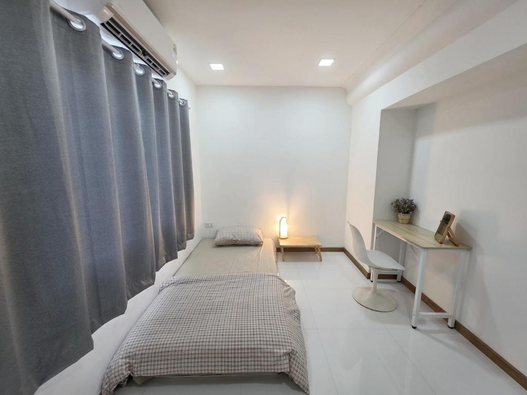 a bedroom with two beds and a desk and curtains at Huggdaily 7 in Ban Khlong Thewa