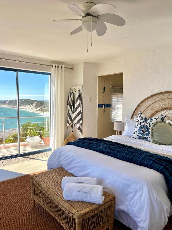 a bedroom with a large bed with a view of the ocean at Endless blue ocean view escape in Langebaan