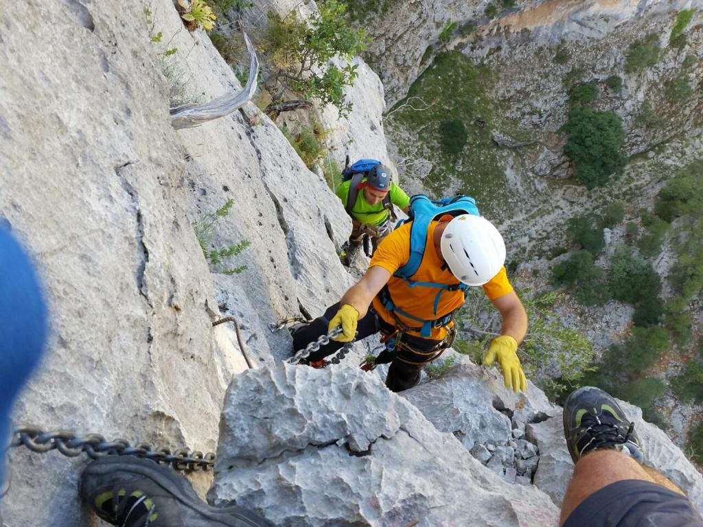 two people climbing on a rocky mountain with a tool at Naramanue in Dorgali