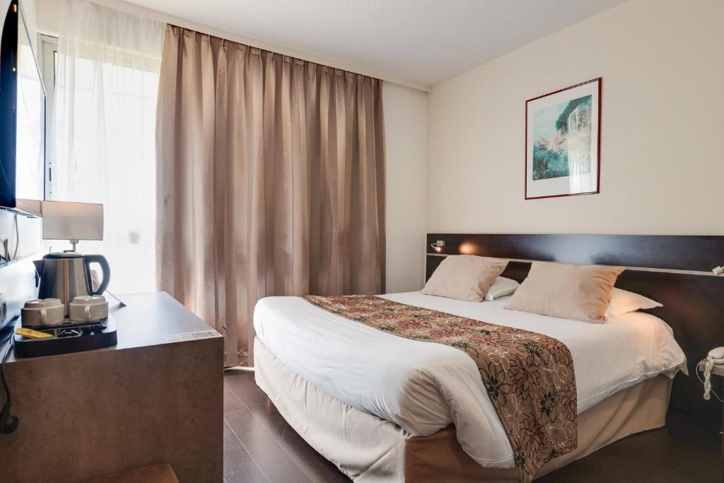 a hotel room with a large bed and a window at Brit Hotel Golfhotel Saint Samson in Pleumeur-Bodou