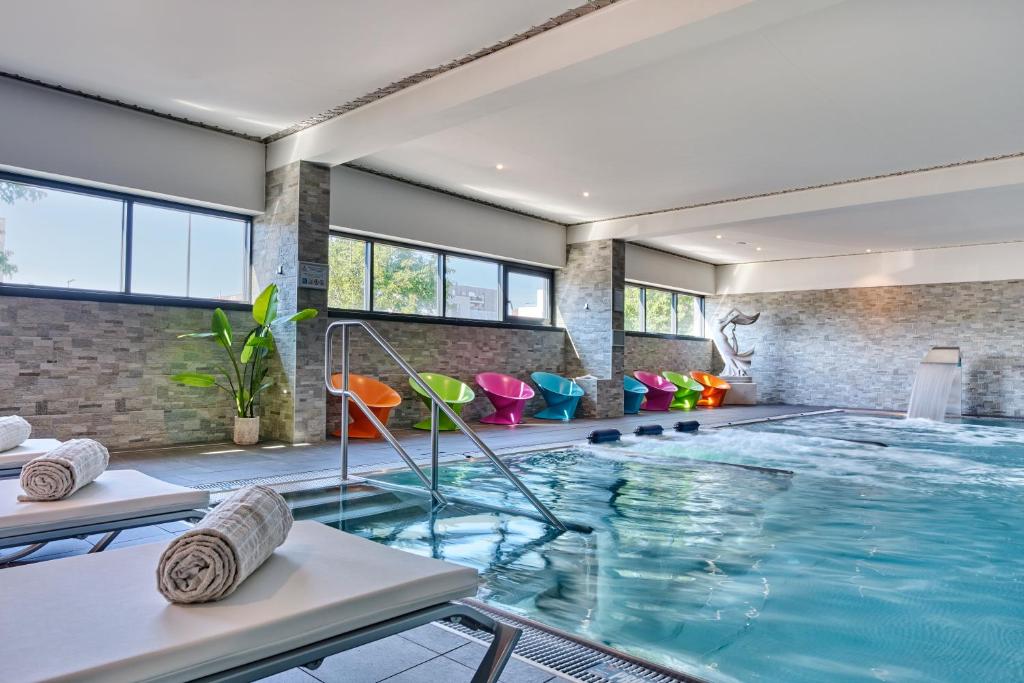 a swimming pool in a house with a room with windows at Hôtel Restaurant Athena Spa in Strasbourg