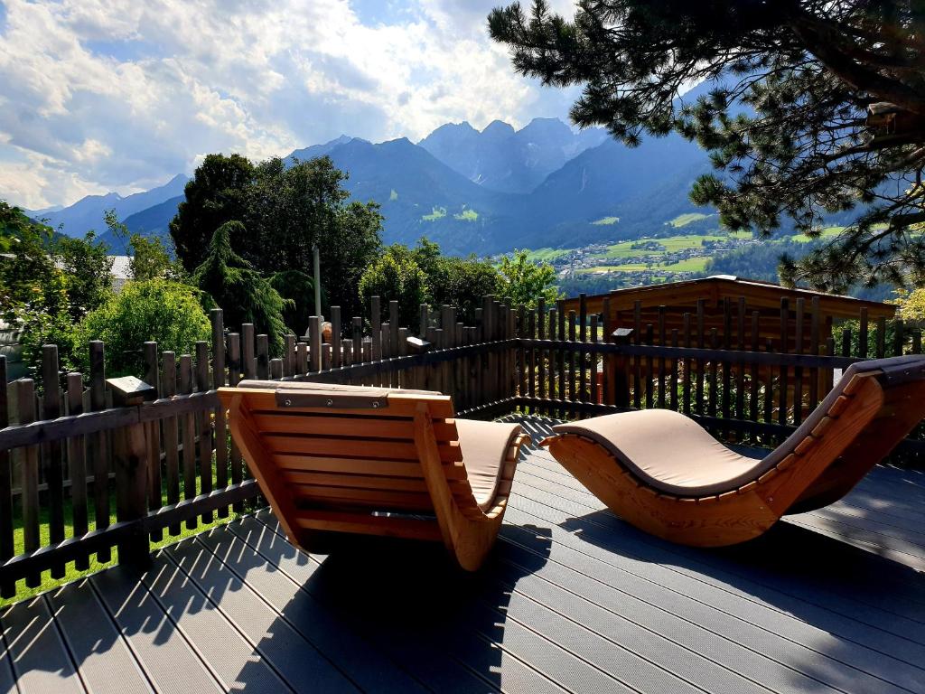 a wooden bench on a deck with a view of mountains at Chalet Gletscherblick Stubai in Mieders