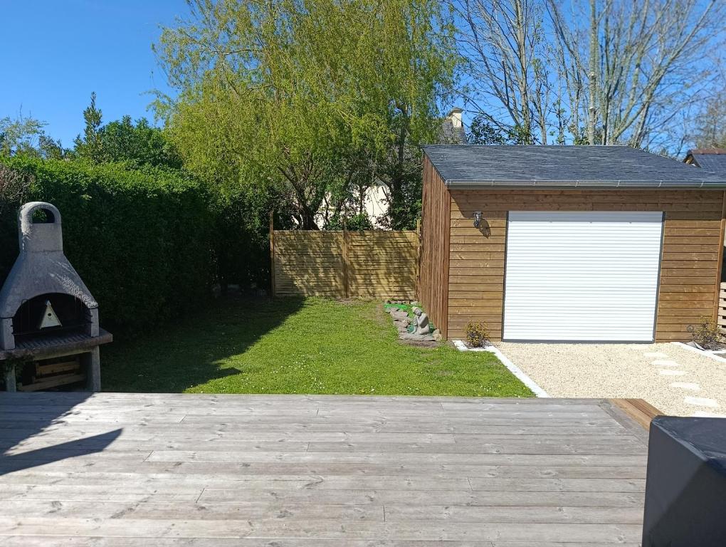 a garage with a white garage door and a yard at Petite Maison a deux pas du centre in Le Faou