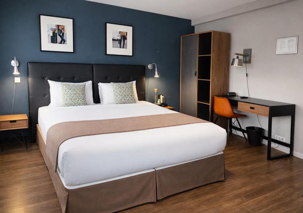 a bedroom with a large bed and a desk at Urban Style Hôtel des Cèdres in Orléans