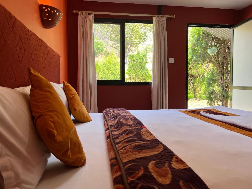 a bedroom with a bed with pillows and a window at Dakshinkali & Dollu Resort in Pharping