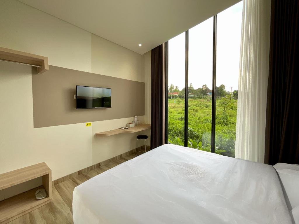 a bedroom with a bed and a tv and a window at Oemah Djari Hotel Syariah Salatiga in Salatiga