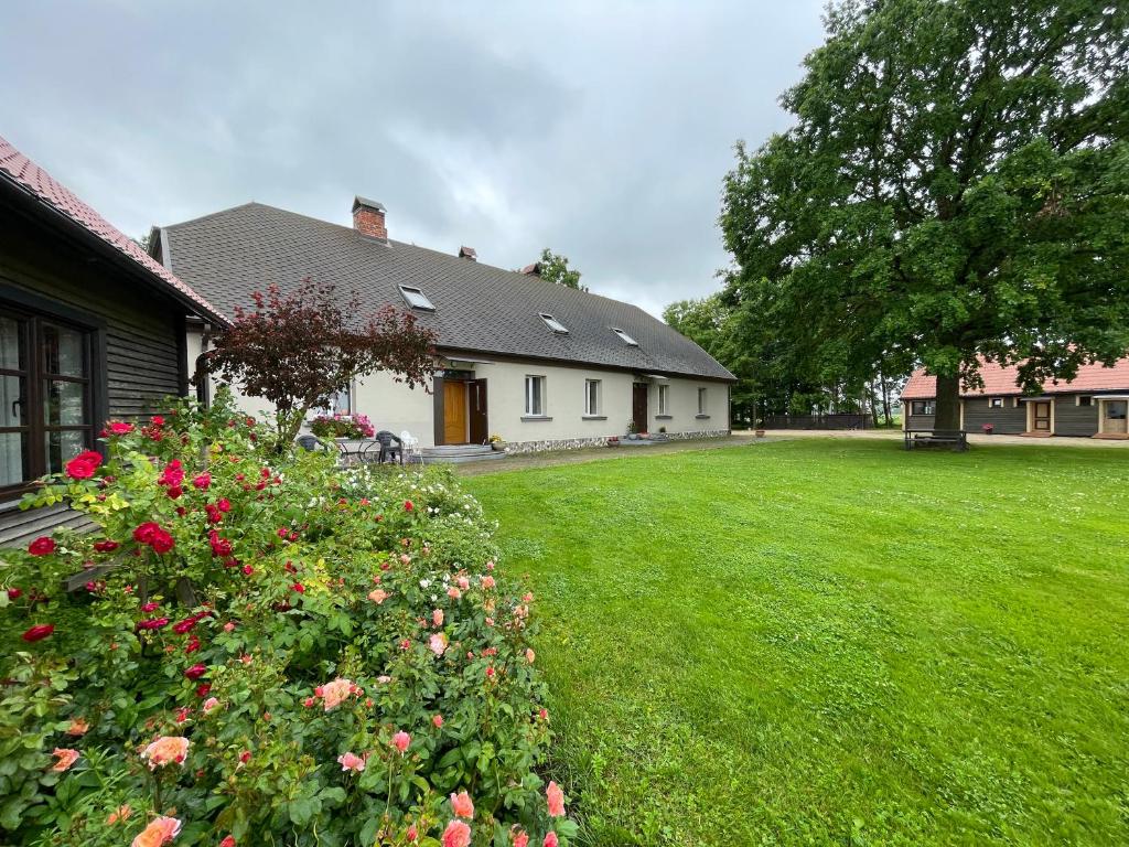 a house with a green yard with flowers at Viesu nams "Vijās" in Degumuiža