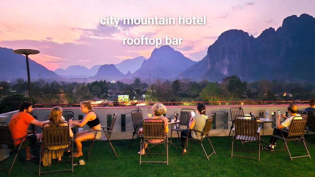 a group of people sitting around a table on a balcony at city mountain hotle in Vang Vieng