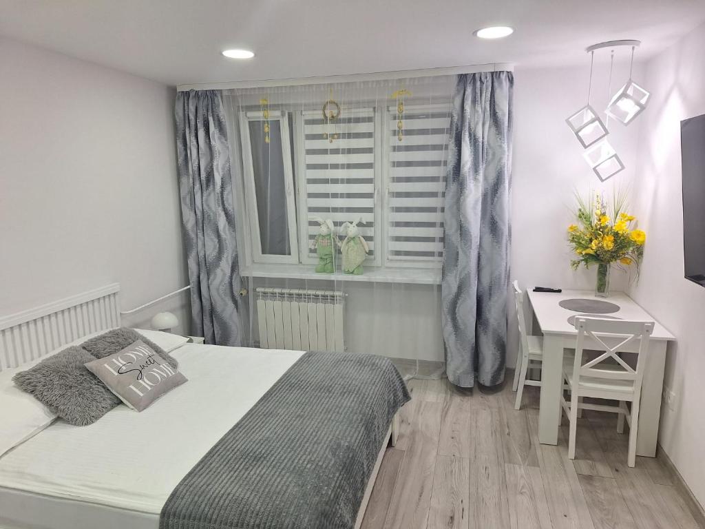 a bedroom with a bed and a table and a window at Apartament Premium Tarnów 2 in Tarnów