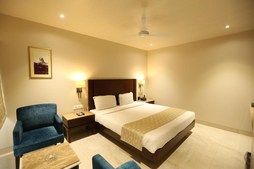 a bedroom with a bed and a blue chair at PRAGATI MANOR in Guwahati