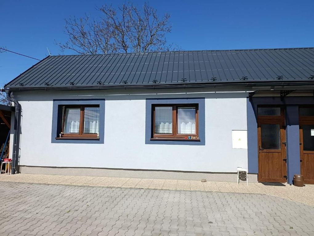 a white house with a black roof and two windows at Dům u Skašků - Žabeň in Žabeň