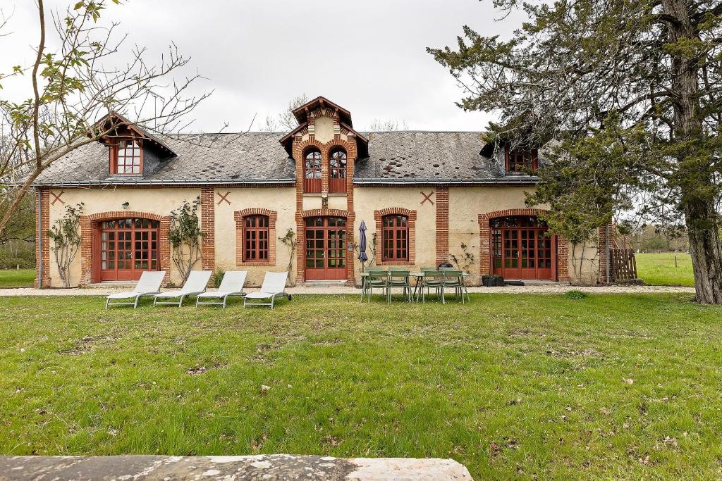 a house with chairs and tables in front of it at Les Ecuries - La Trigalière in Ambillou