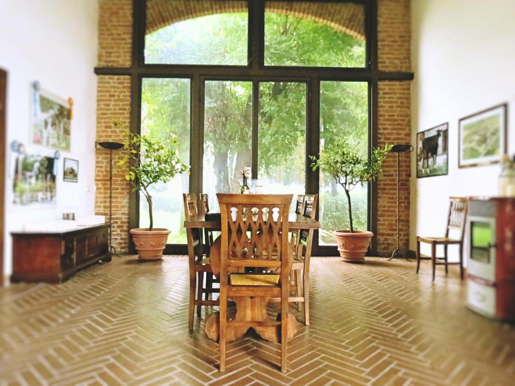 una stanza con tavolo e sedie e una grande finestra di Agriturismo Cascina Nuova a Cremona