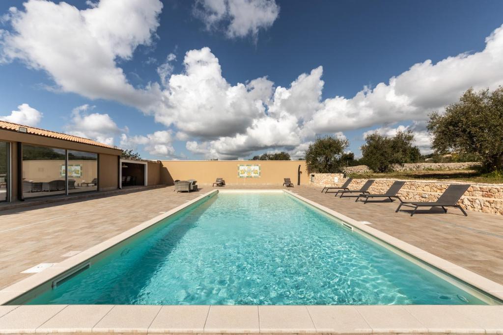 a swimming pool with chairs and a house at Villa Meti in Avola