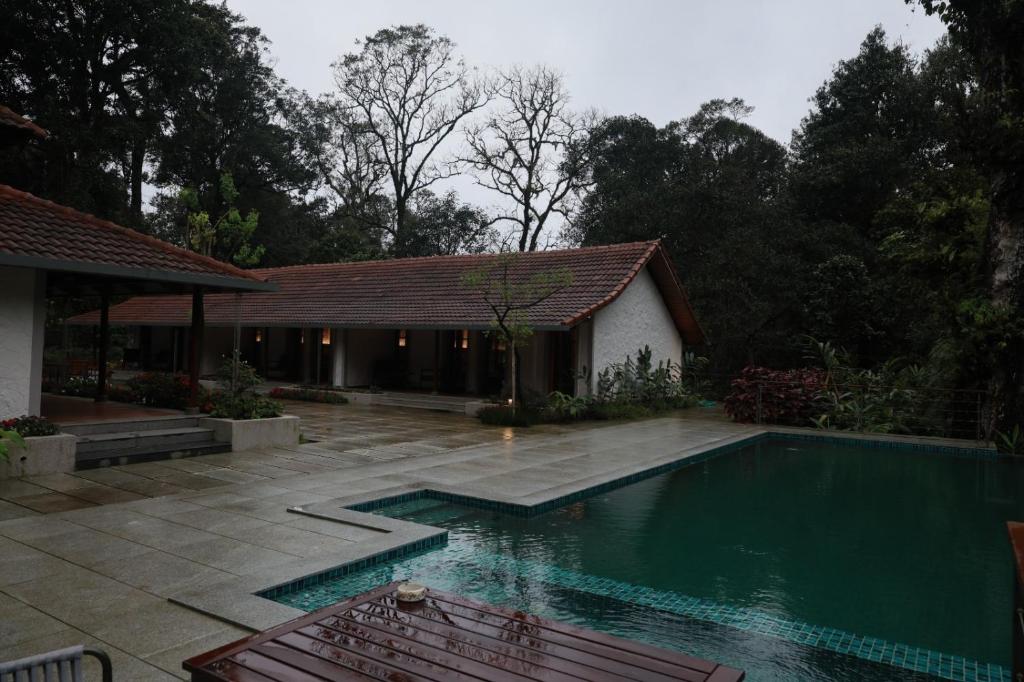 a swimming pool in front of a house at Aelam Acres in Chillithodu