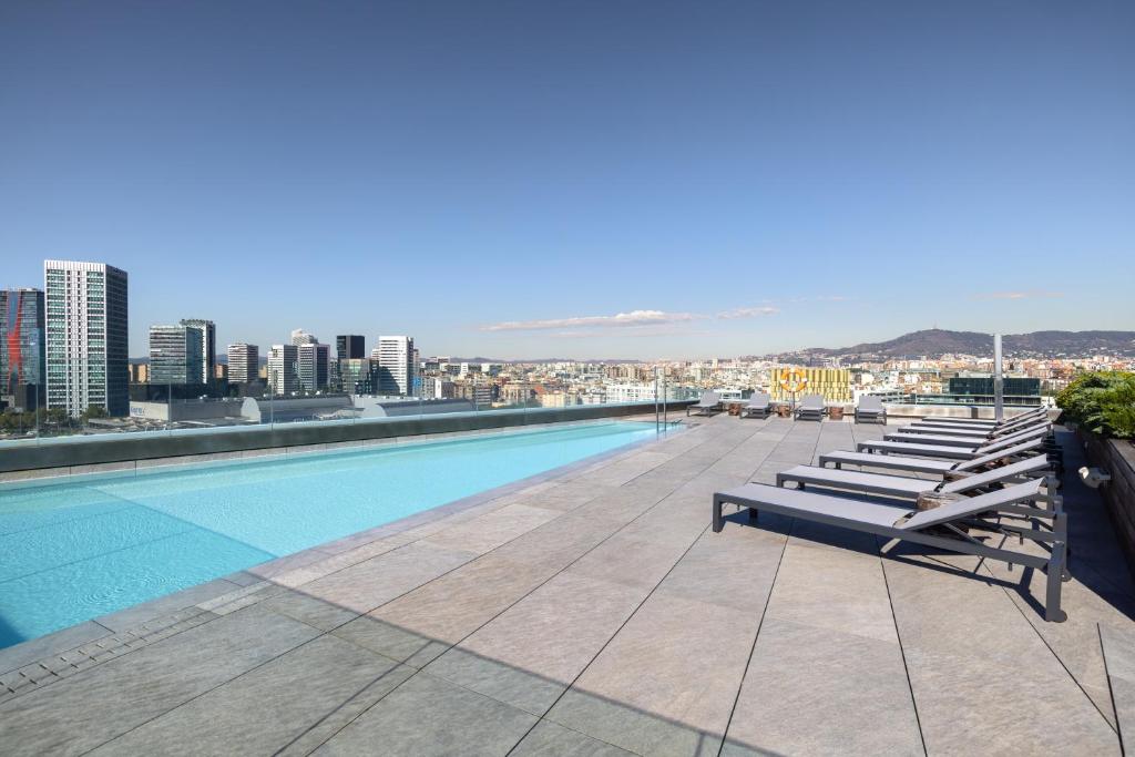 a pool on the roof of a building with lounge chairs at Hotel SB Plaza Europa in Hospitalet de Llobregat