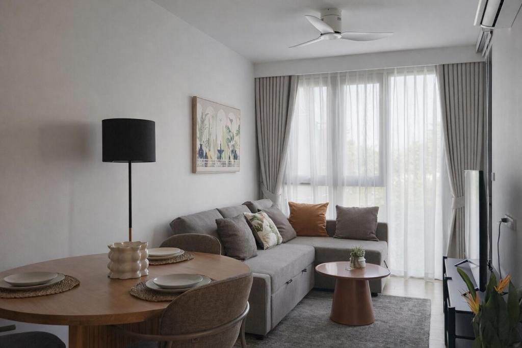 a living room with a couch and a table at Skypark Celeste with stunning golf course view in Laguna Phuket