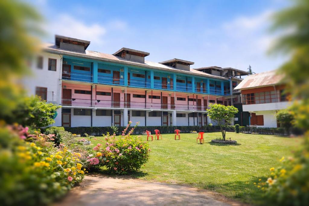 a large building with red chairs in front of it at Hotel New Sahil - Srinagar in Srinagar