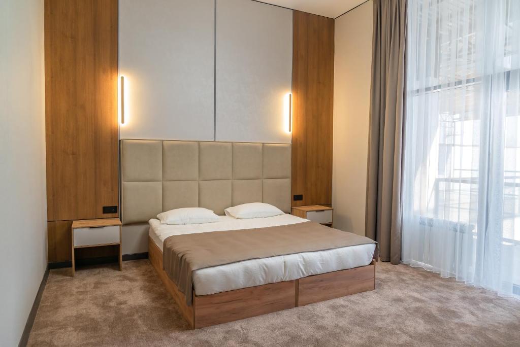 a bedroom with a large bed and a large window at Nord Karakol Hotel in Karakol