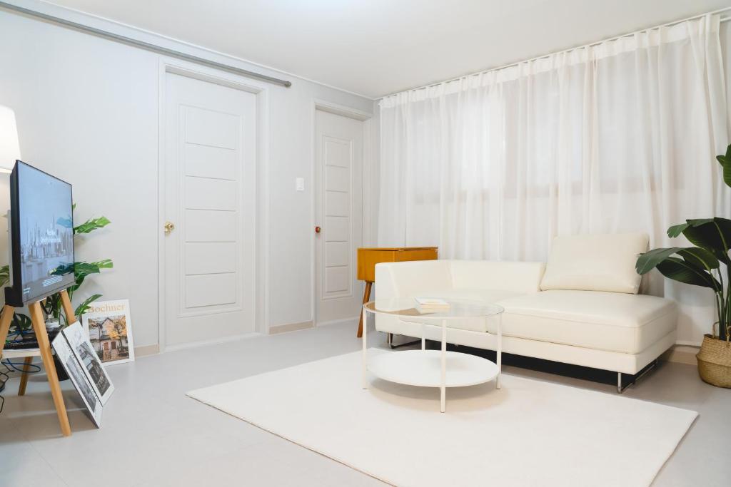 ein Wohnzimmer mit einem weißen Sofa und einem Tisch in der Unterkunft 스테이솜 in Daejeon