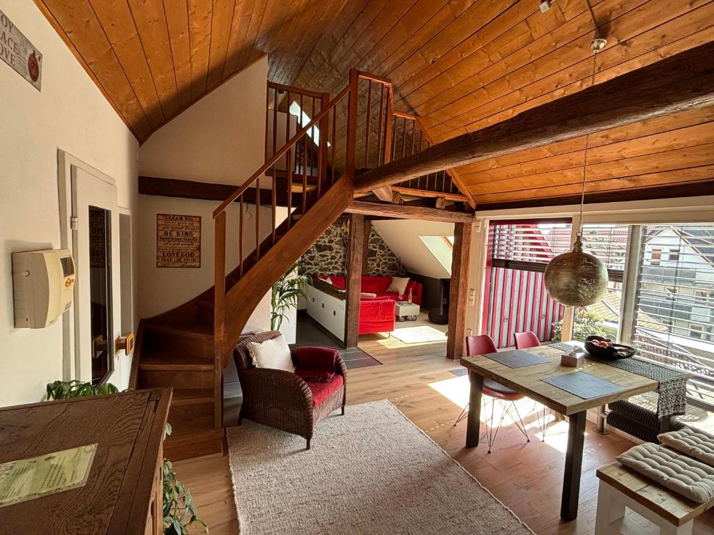 a living room with a wooden staircase and a table at Historische Ferienwohnung mit Sauna und Dachterrasse in Lich
