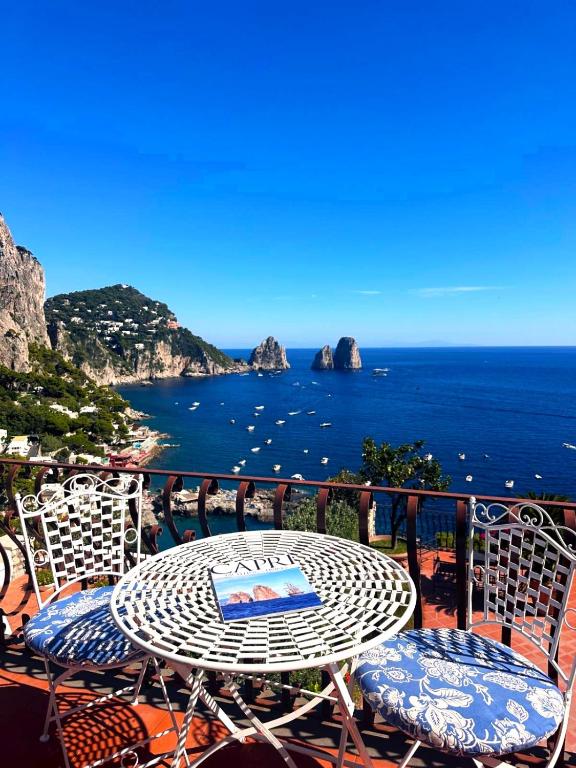 a table and chairs on a balcony overlooking the ocean at Casa vista Faraglioni Capri in Capri